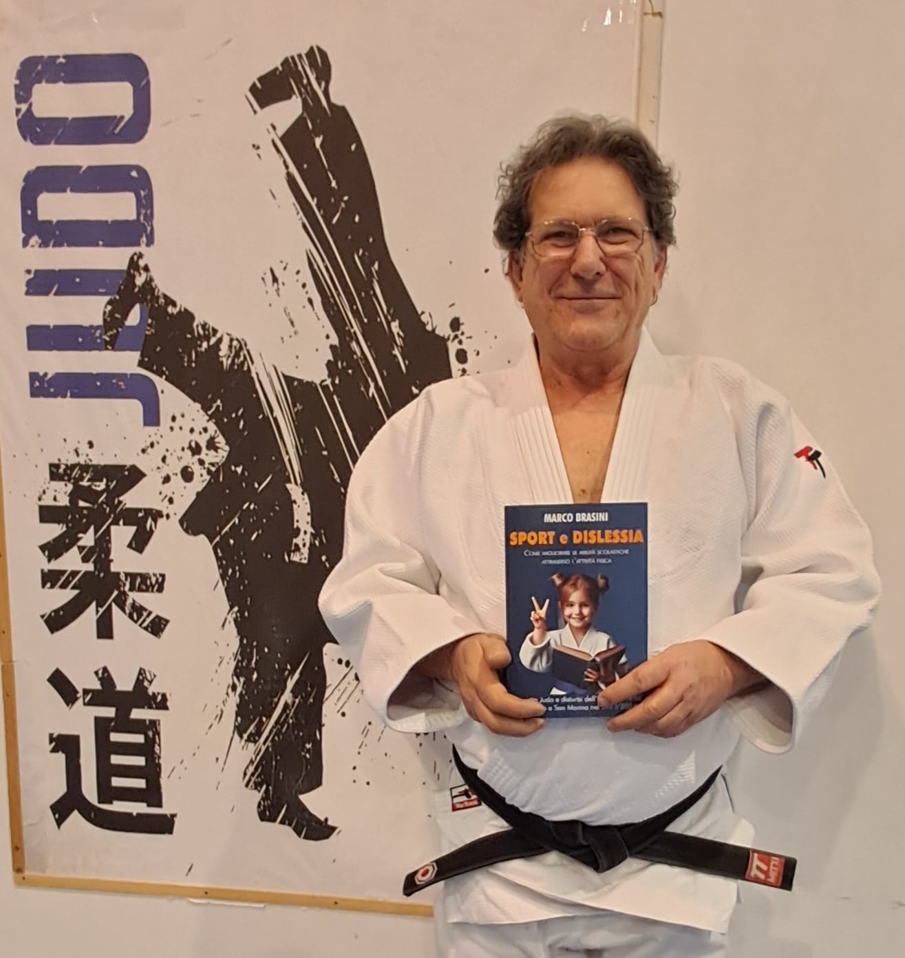 Immagine di Marco Brasini col libro (Sport e Dislessia) scritto dalla 
              sua esperienza del 2023 con un corso specifico per bambini DSA 
